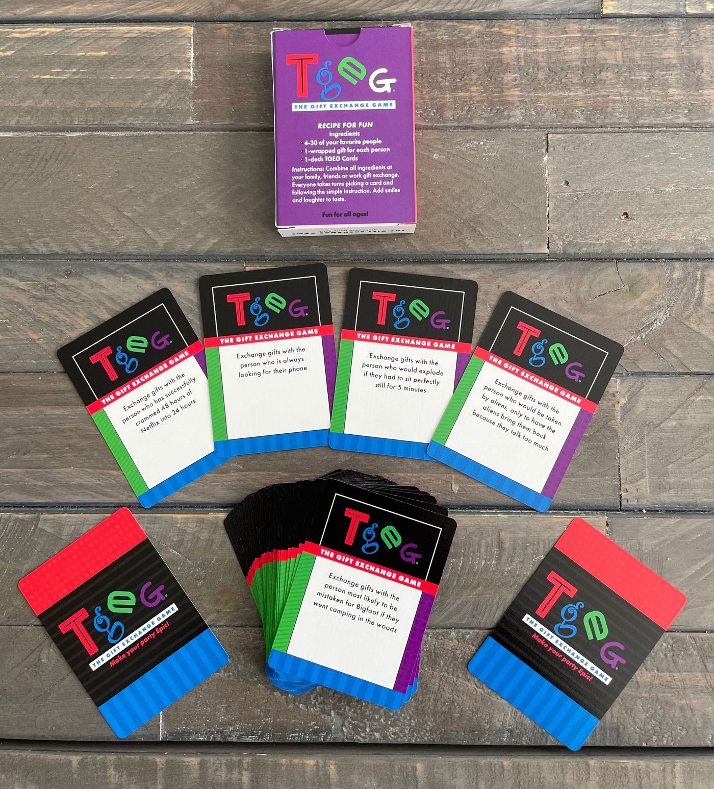 The purple TGEG box, four cards fanned out, the rest of the deck and two cards face down on a wood table